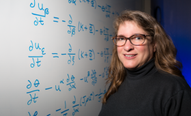 Carol Woodward standing by white board with algorithms