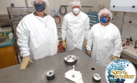 Three resesarchers wearing masks behind table with clylindrical objects